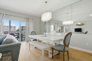 A dining area with a white table, benches, and chairs, a large mirror, and a chandelier. - Directly Across from Gulf with Views from Every Balcony! The Easiest Access! (Navarre)