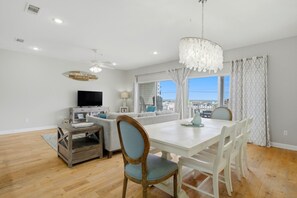A dining area with a white table, chairs, and a chandelier.
