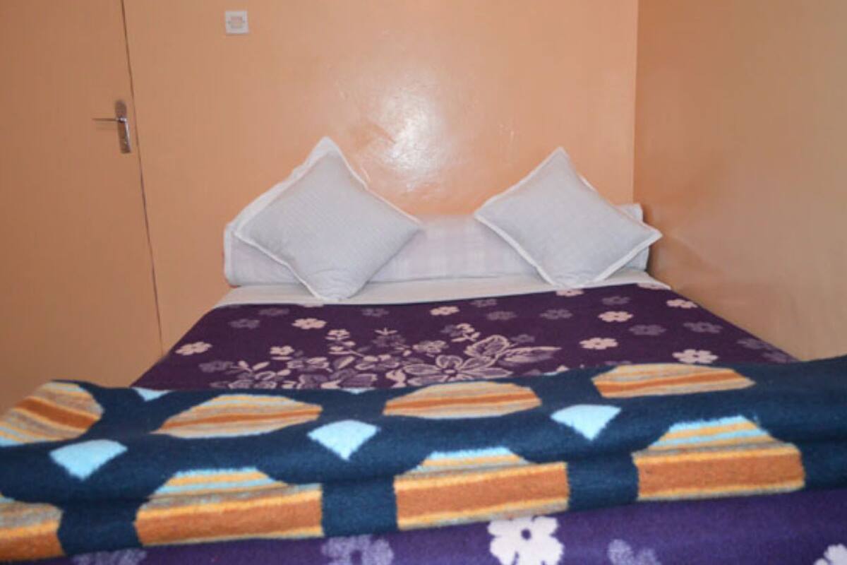Un lit recouvert d’une couvre-lit à motifs floraux violets et agrémenté de deux oreillers blancs.