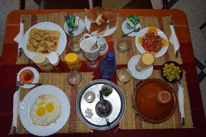 A table set with various dishes including eggs, bread, and olives, suggesting a breakfast or brunch setting.