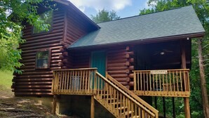 Eine Blockhütte mit einer Holzdiele und einer Treppe, die zu einer grünen Tür führt.
