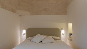 Ein Schlafzimmer mit einem großen Bett, zwei Wandleuchten und einer Steindecke.