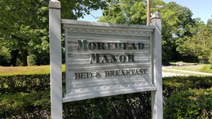 Letrero de Morehead Manor Bed & Breakfast, con un diseño rústico de madera que muestra claramente el nombre y tipo de alojamiento.