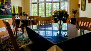 Un comedor con mesa de vidrio, sillas de madera y un centro de mesa con flores.