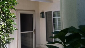 A building with a white exterior, a door with a glass panel, and a window with shutters. - Cool Summers + Warm Winters on 18 Hole Golf Course (Escondido)