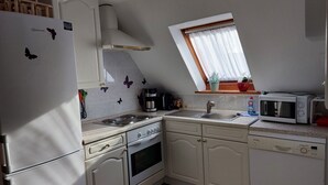 A compact kitchen with white cabinets, a built-in oven, a microwave, and a sink. - Apartment at the old Greetsieler Tief (Eilsum)