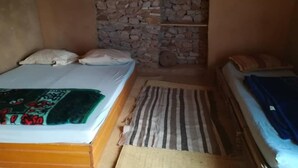 Ein Zimmer mit einem Bett, einem kleinen Tisch und einer Steinwand.