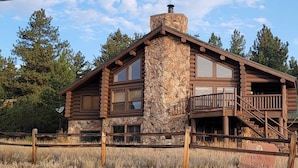 A log cabin with a stone chimney, large windows, and a balcony. - Black Tree Resort (Lake George)