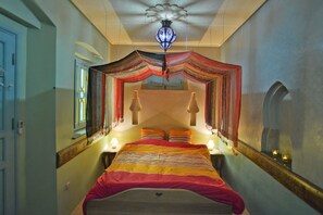 Ein Zimmer mit einem Bett, einer Chandelier und einem Spiegel.