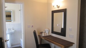 A hotel bathroom with a sink, mirror, and a small table with toiletries. - Hawthorn House (Blackpool)