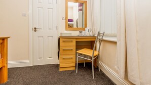 A small, neatly organized bedroom with a wooden desk, a chair, a mirror, and a window with curtains. - Hawthorn House (Blackpool)