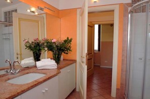 Un baño con lavamanos, espejo y zona de ducha.