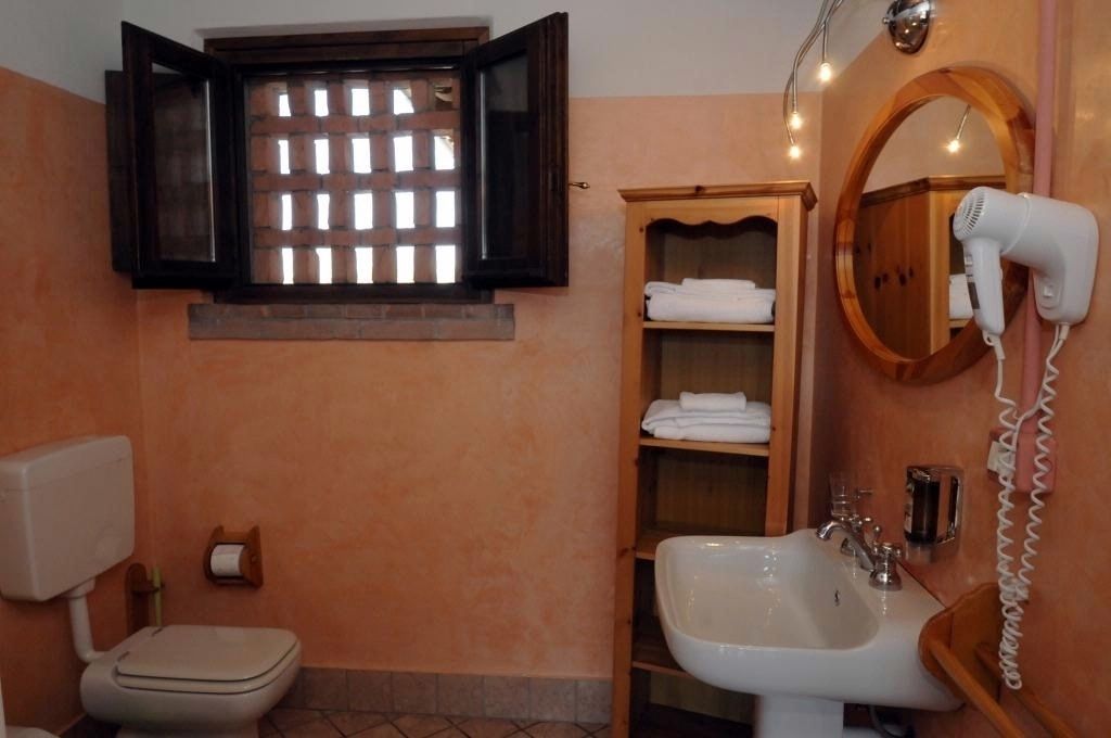 Un baño con inodoro, lavamanos y un secador de pelo montado en la pared.