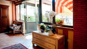Una habitación con un aparador de madera, una silla, un ventanal con vistas al exterior y una alfombra estampada.