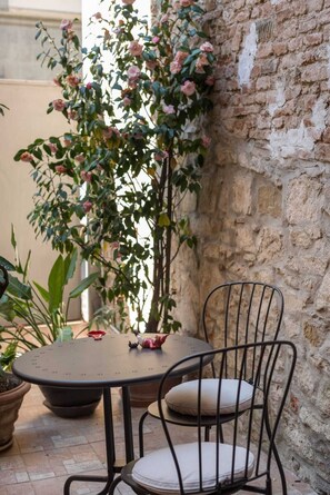 A round table with a metal chair and a potted plant with pink flowers. - Art Gallery Apartment in Florence (Florence)