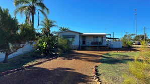 A single-story house with a covered porch, a small attached garage, and a paved driveway. - The Secret Waypoint - Kalbarri, WA (Kalbarri)