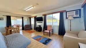 A spacious living area with a dining table, two sofas, a TV, and a window with curtains. - The Secret Waypoint - Kalbarri, WA (Kalbarri)