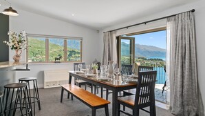 Ein Essbereich mit Tisch für vier Personen, einer Bank und Blick auf einen See und Berge.