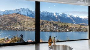 Eine Küche mit einem großen Fenster und Blick auf einen See sowie schneebedeckte Berge.
