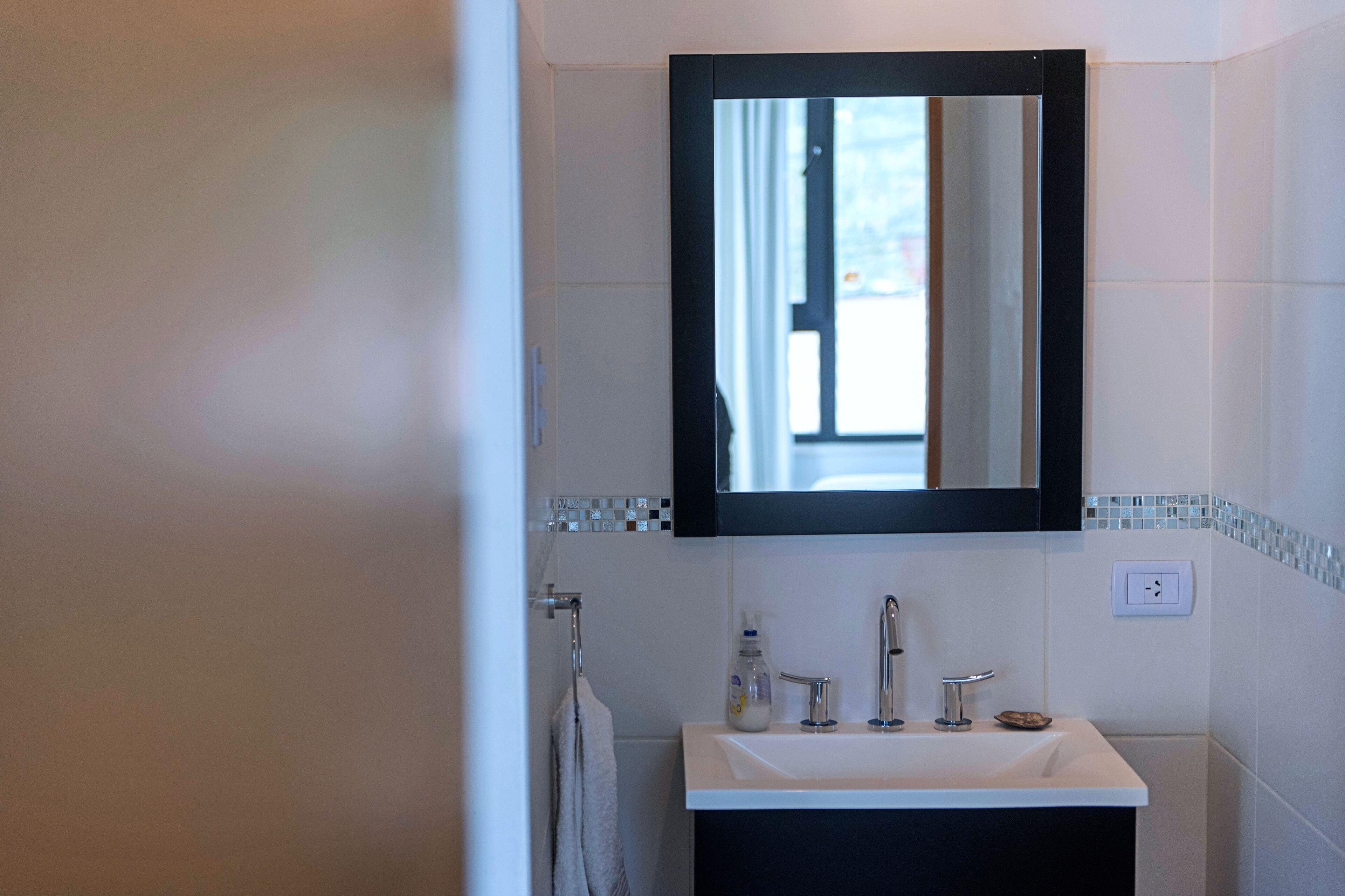 A bathroom with a white sink, a mirror, and a window.