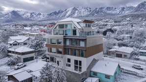 Een meerlaags gebouw met een modern ontwerp, gelegen in een besneeuwde stad met bergen op de achtergrond.