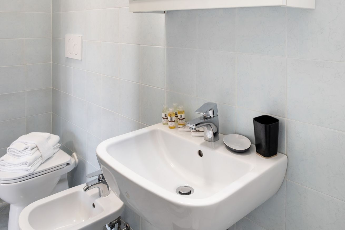 A bathroom with a white sink, a bidet, and a toilet.