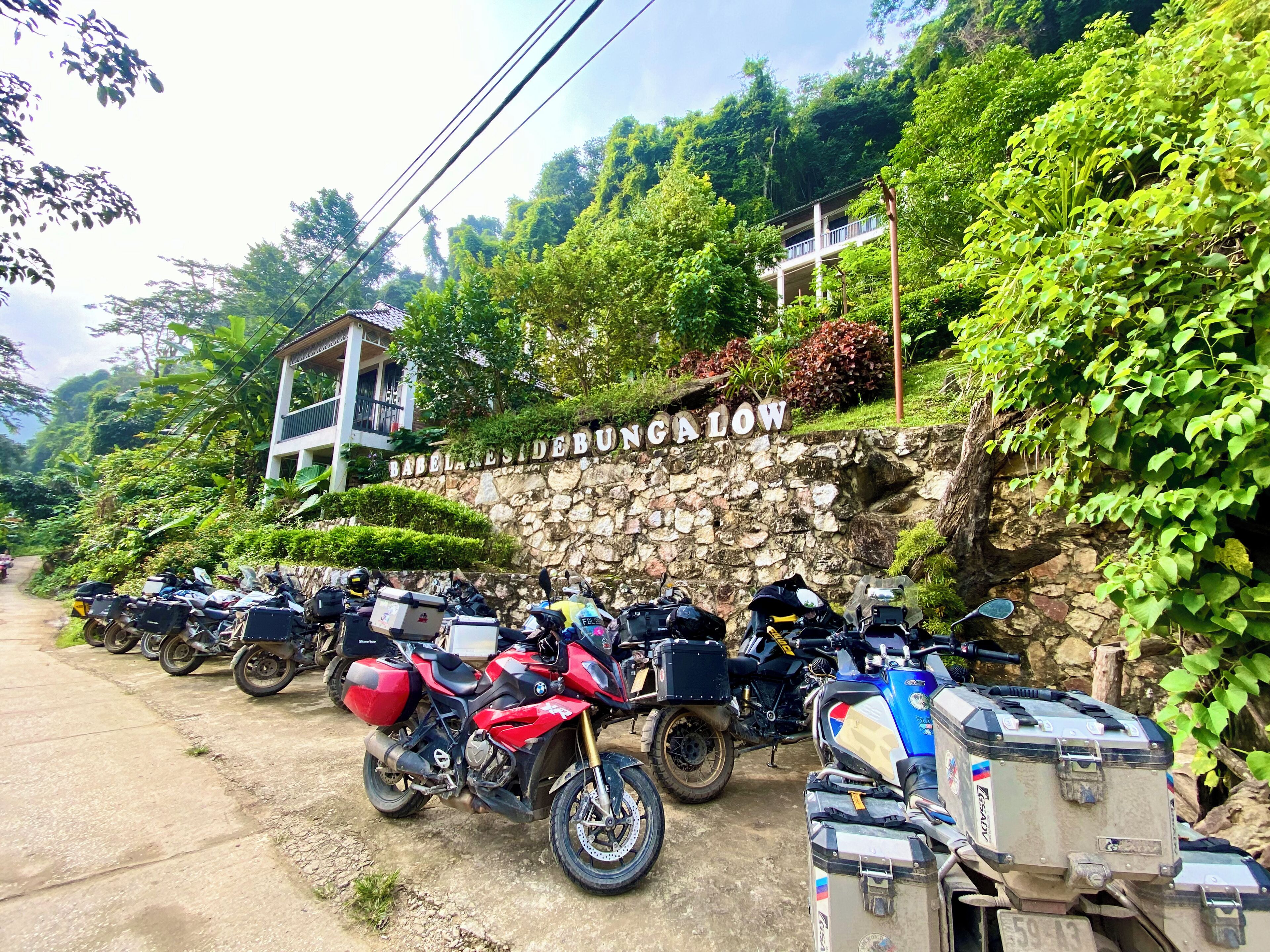 Mur de pedra amb un senyal que diu "BABBLESIDE BUNGALOW" i una filera de motocicletes aparcades.