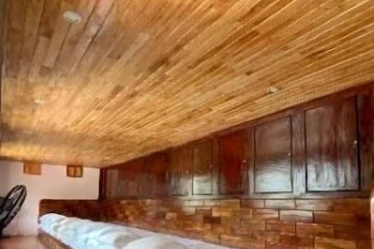 Una habitación con un banco de madera largo, techo de madera y pared de ladrillo.