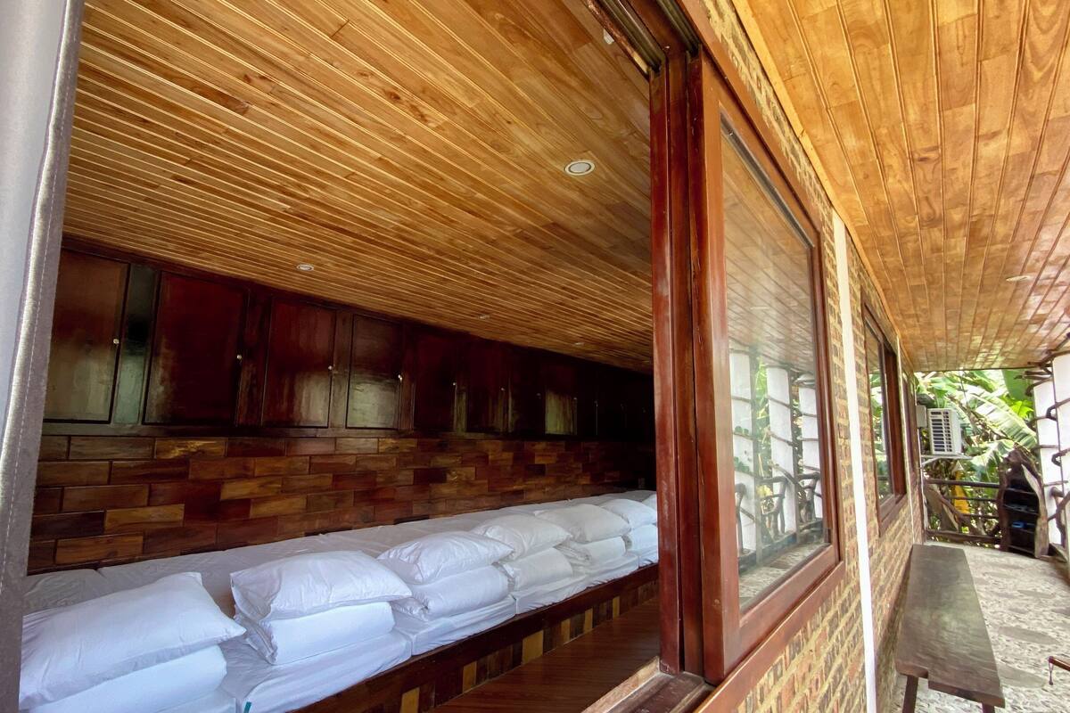 Una habitación con techo de madera, una cama con ropa de cama blanca y una pared de ladrillo.