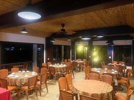Um restaurante com várias mesas redondas, cada uma disposta com cadeiras e toalhas.
