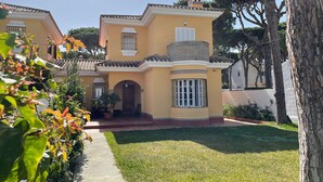 A two-story house with a tiled roof, a small balcony, and a well-maintained lawn. - Spacious holiday home by the sea (Chiclana de la Frontera)
