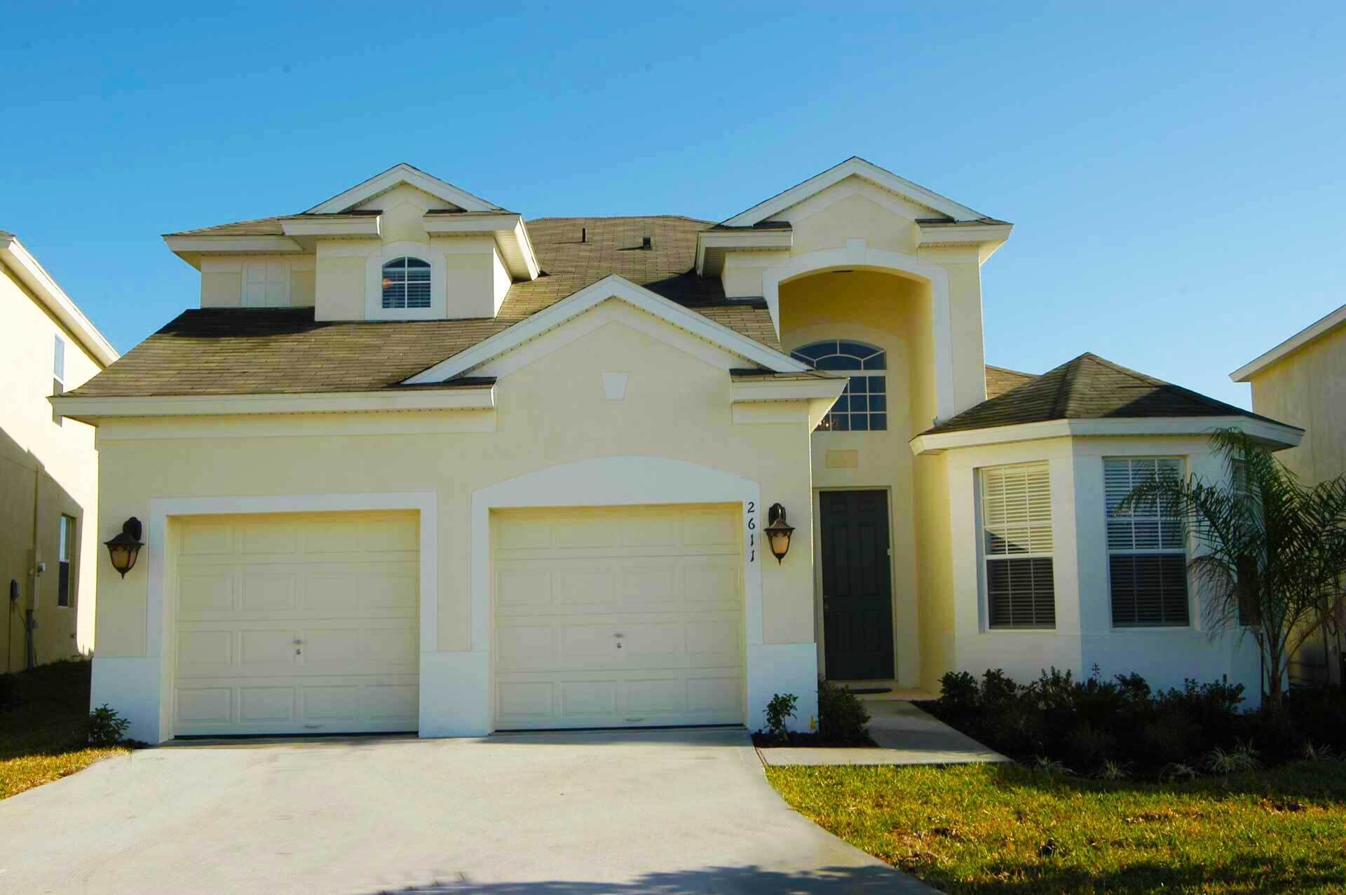 A two-story house with a central garage, a small attached garage, and a single-story wing with a chimney.