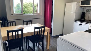 Une cuisine compacte comprenant une table à manger, des chaises, un réfrigérateur, un four à micro-ondes et un lave-vaisselle.