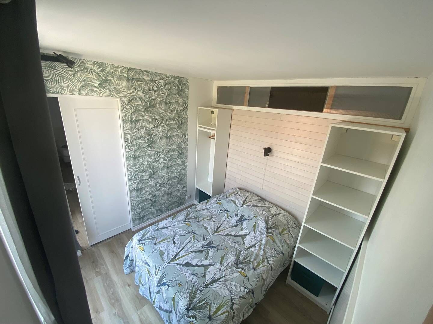 Ein Schlafzimmer mit einem Bett, einem Kleiderschrank und integrierten Regalen.