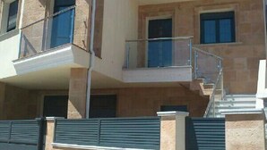 A multi-story residential building with balconies, a staircase, and a gated entrance. - Lodging AT-CC-00296,Extremadura,garden,private garage,air conditioning, hydromassage, air conditioning, heating, air conditioner, heating, air conditioner, heating, air conditioner, heating (Zarza de Granadilla)