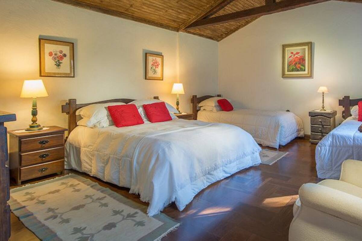 Un dormitorio con dos camas, un escritorio y una silla. Hay dos mesitas de noche con lámparas.