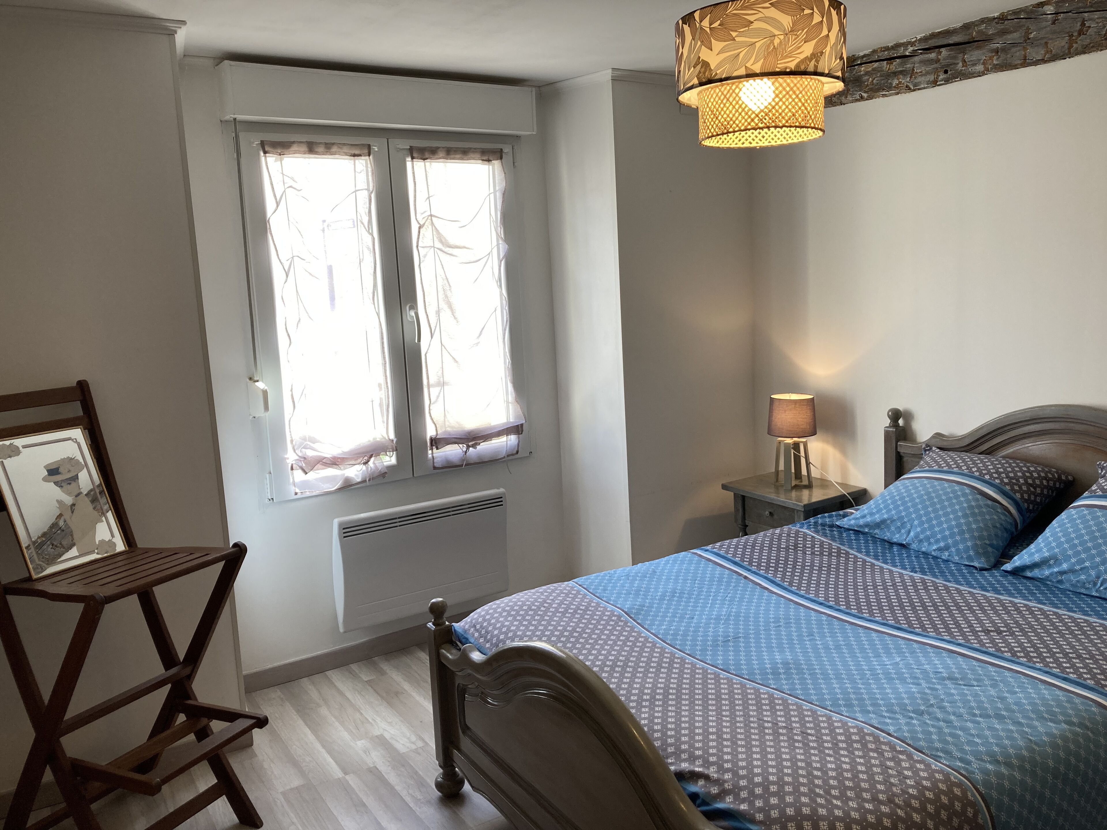 A bedroom with a bed, bedside table, lamp, and a window with curtains.