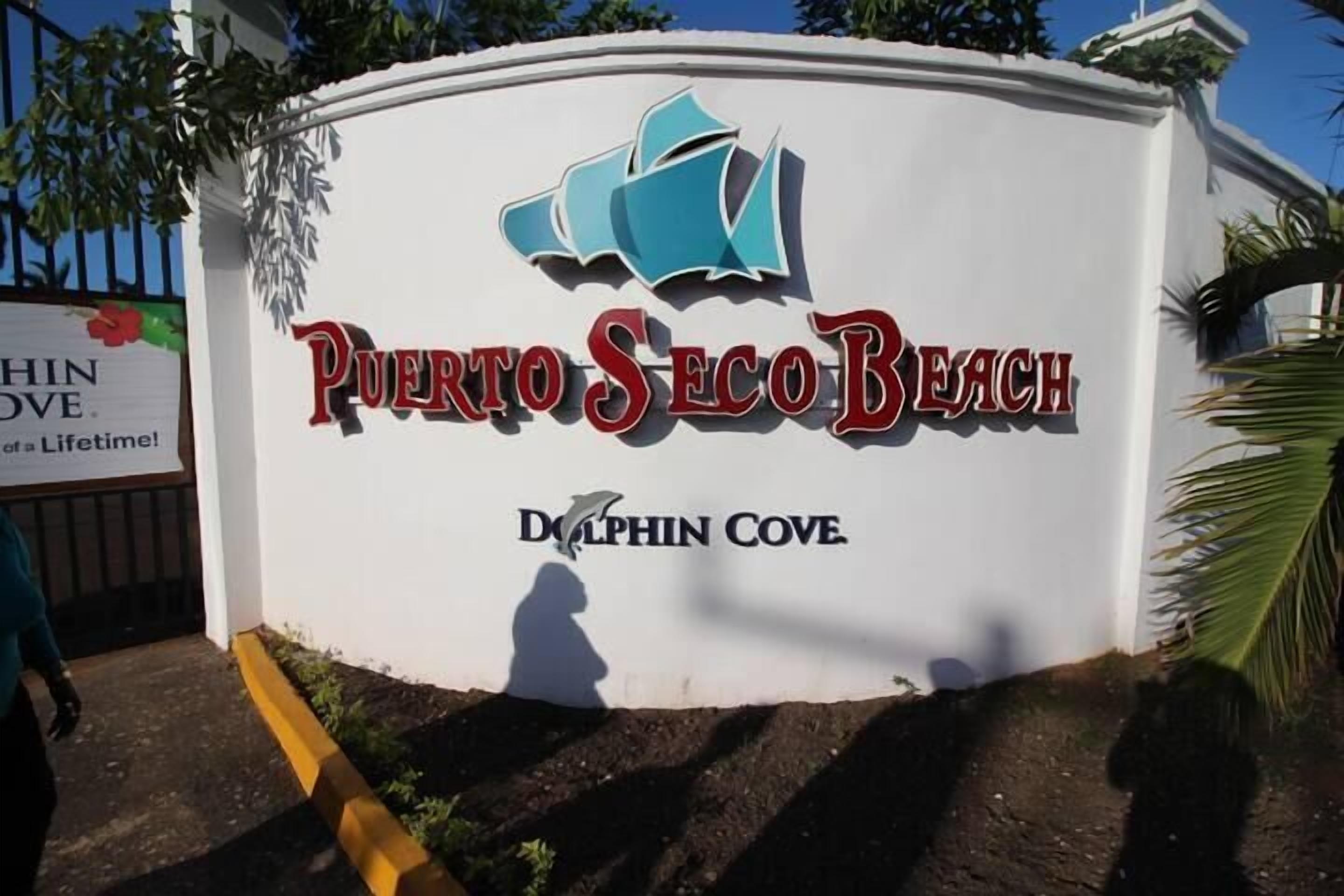 A sign for Puerto Seeco Beach with the Dolphin Cove logo.