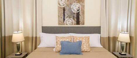 A hotel room with a bed, two nightstands, a wall-mounted air conditioner, and curtains.