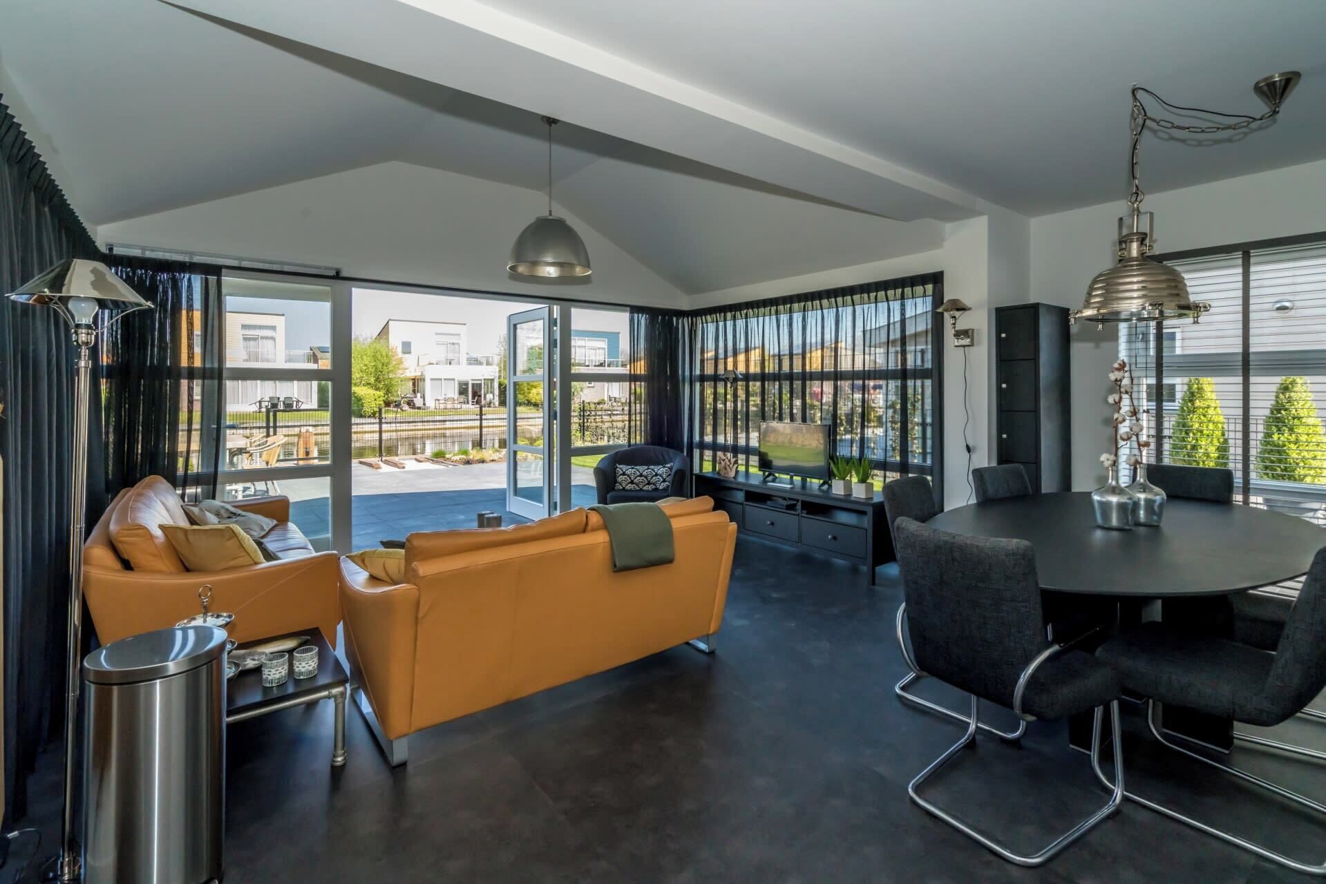 Un salon moderne comprenant un canapé, une table à manger et des chaises, de grandes fenêtres offrant une belle vue et un ventilateur de plafond.