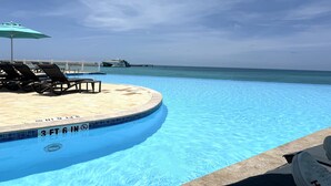 A pool with lounge chairs and a view of the ocean. - Best of Bimini - Oceanview - 2 Bedroom / 2 Bath (Bimini)