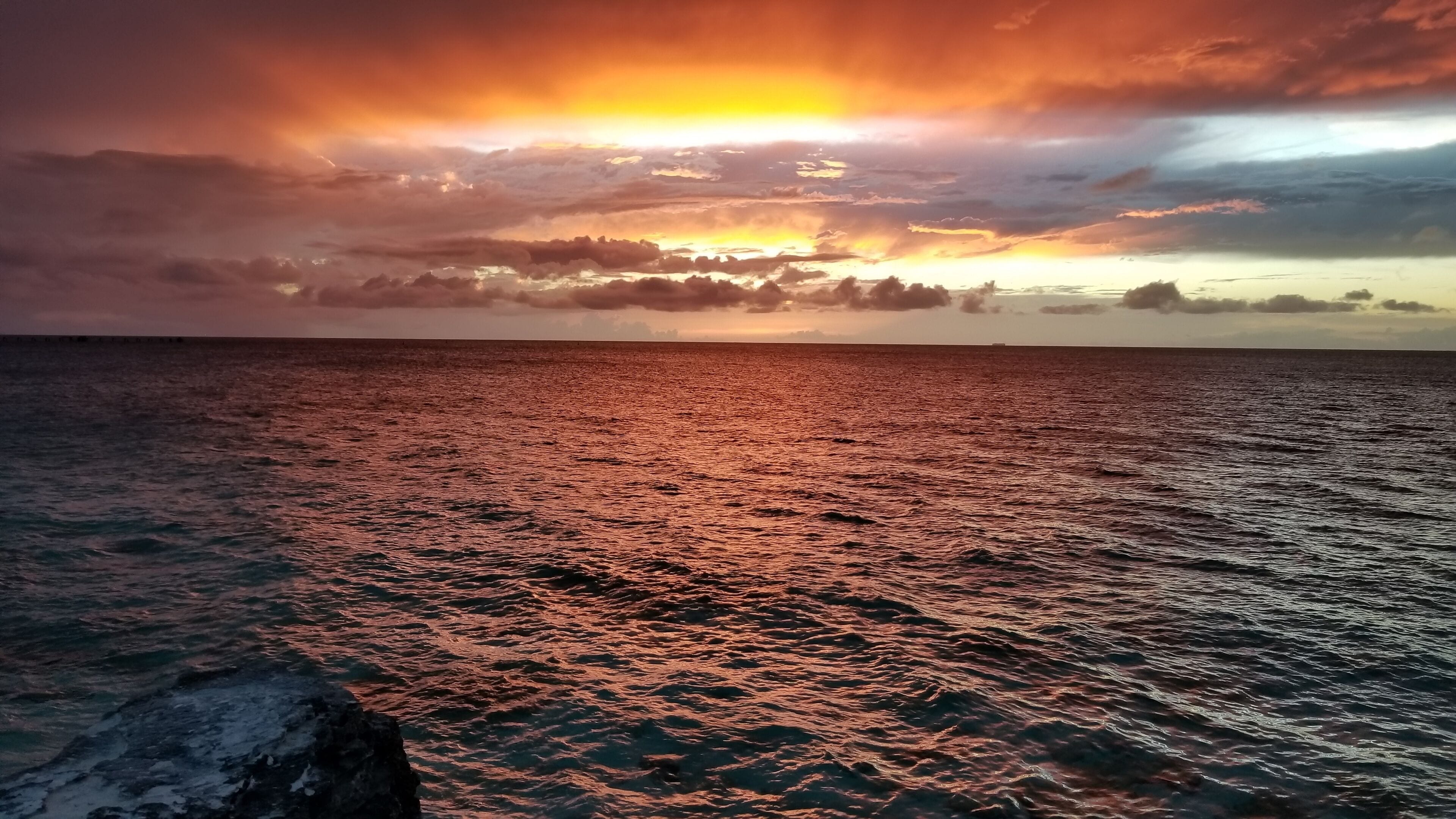 En solnedgång över en vattenyta med en klippig kust.