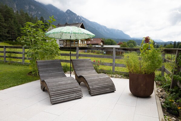 A patio with two wooden loungers and a potted plant.