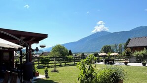 Un patio con mobiliario exterior, cerca de madera y vista a la montaña.