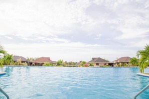A swimming pool surrounded by resort-style buildings with a clear sky. - Sea Breeze Villa at Coolshade (St. Ann's Bay)
