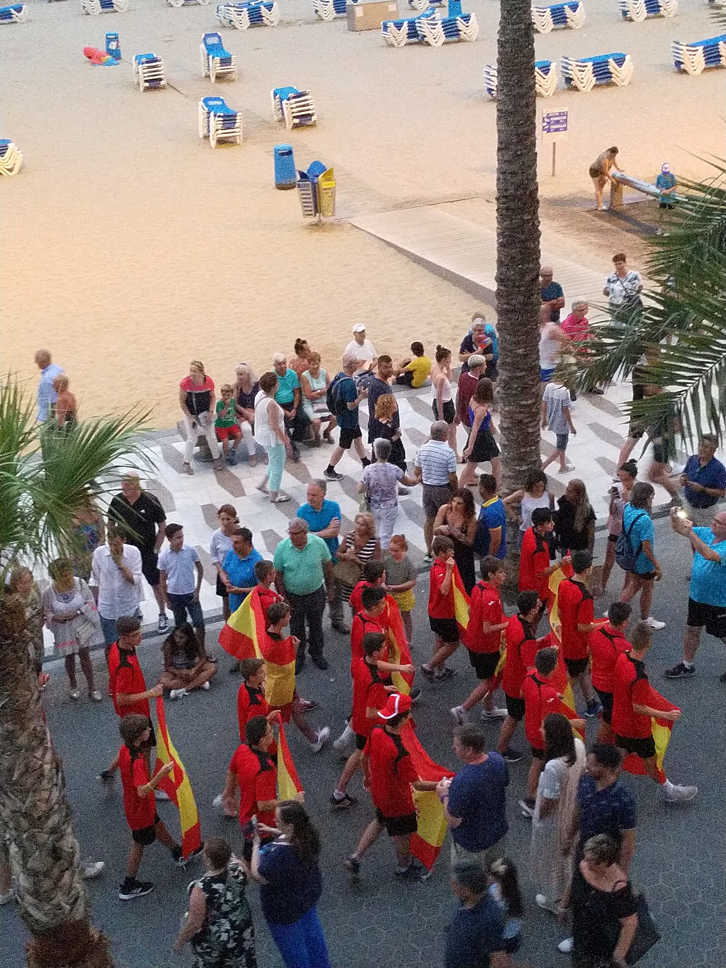 A crowded outdoor area with people, some in red and yellow uniforms, and others in casual clothing.