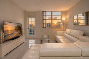 A modern living room with a television, sofa, and a glass coffee table. - Spacious 3-Bedroom Retreat with Panoramic City & Bay Views in Sunny Isles Beach (Sunny Isles Beach)