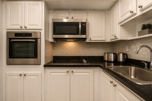 A modern kitchen with white cabinets, stainless steel appliances, and a black countertop.