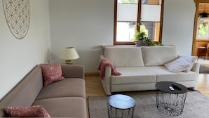 A living room with a beige sofa, a small round coffee table, and a window with blinds. - Welcome to the "Hohe Liebe" vacation apartment (Bad Schandau-Ostrau)