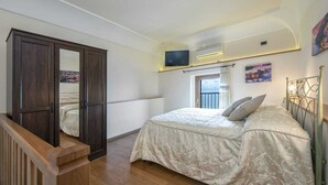 Une chambre à coucher avec un lit, une armoire, une télévision et une fenêtre donnant sur un beau paysage.